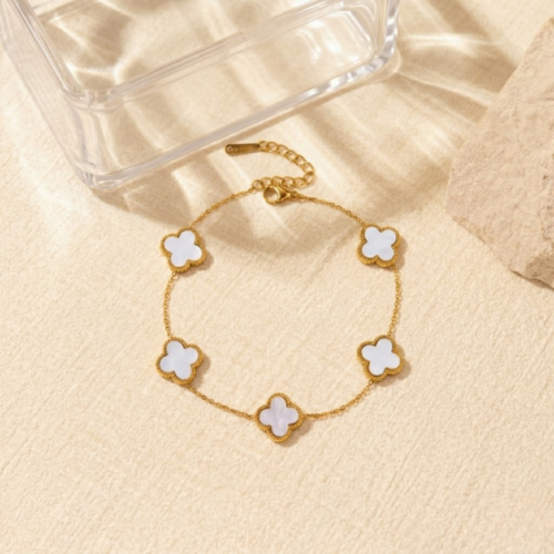 The Gift Maison 18K gold five motif luxury white clover bracelet on a stone aesthetic backdrop