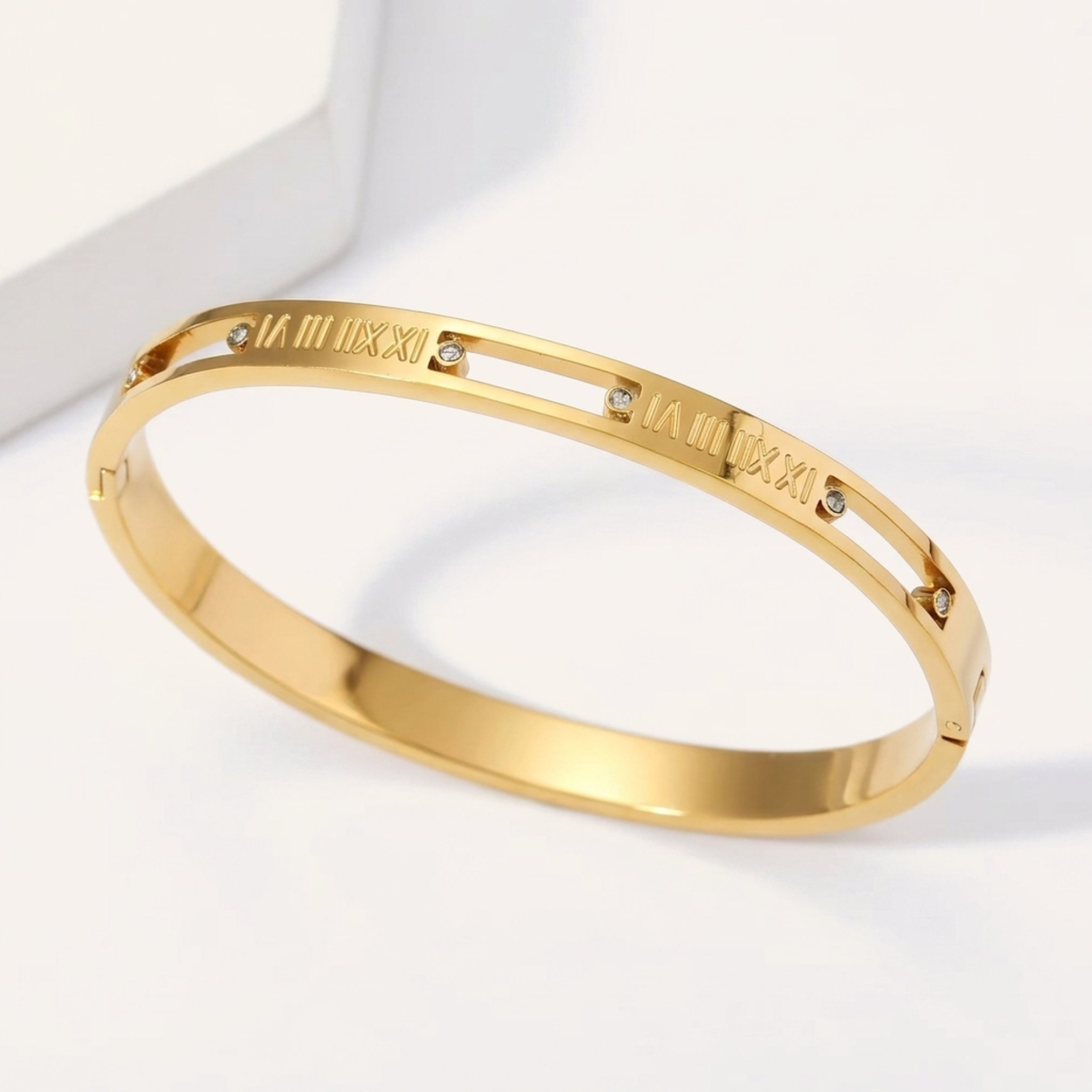 Front view of a wide 18K gold plated roman numeral bangle on a cream background