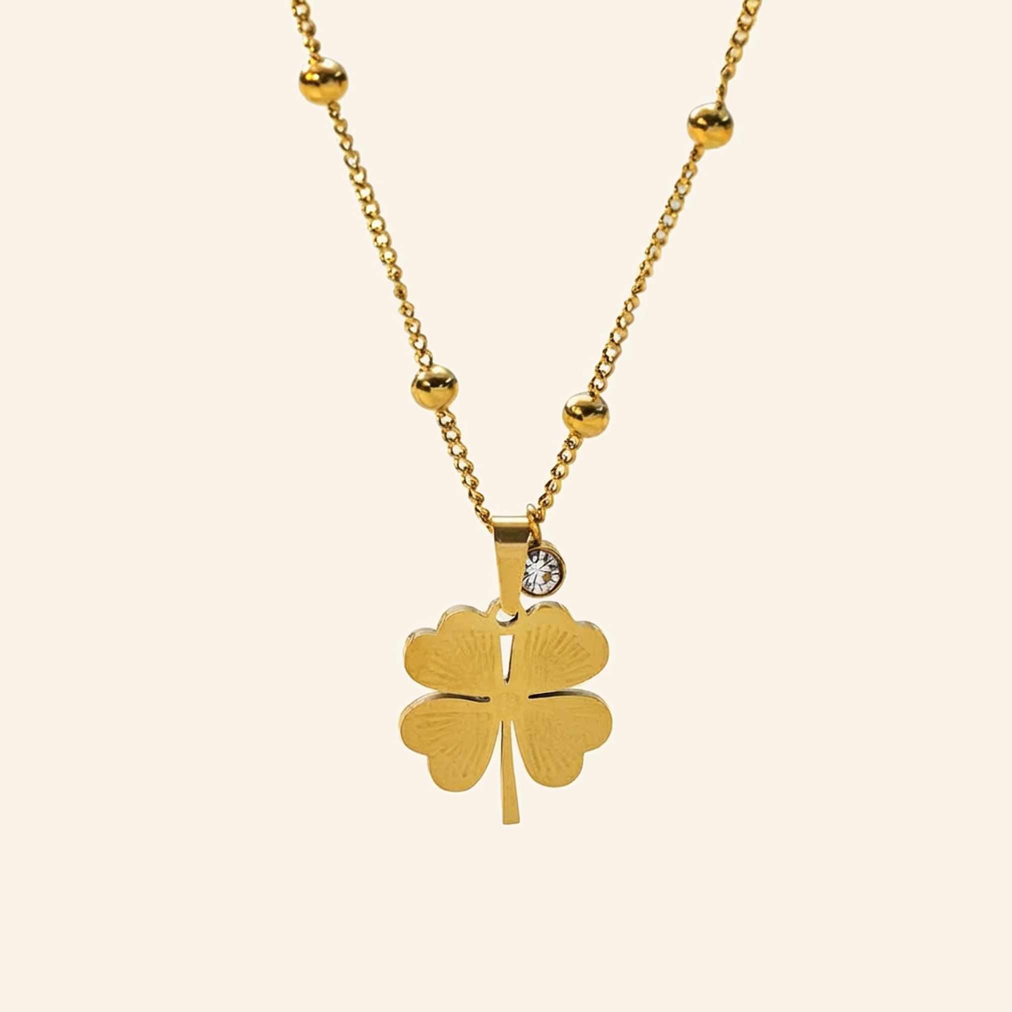 Gold lucky charm necklace with a polished clover pendant on a beaded chain