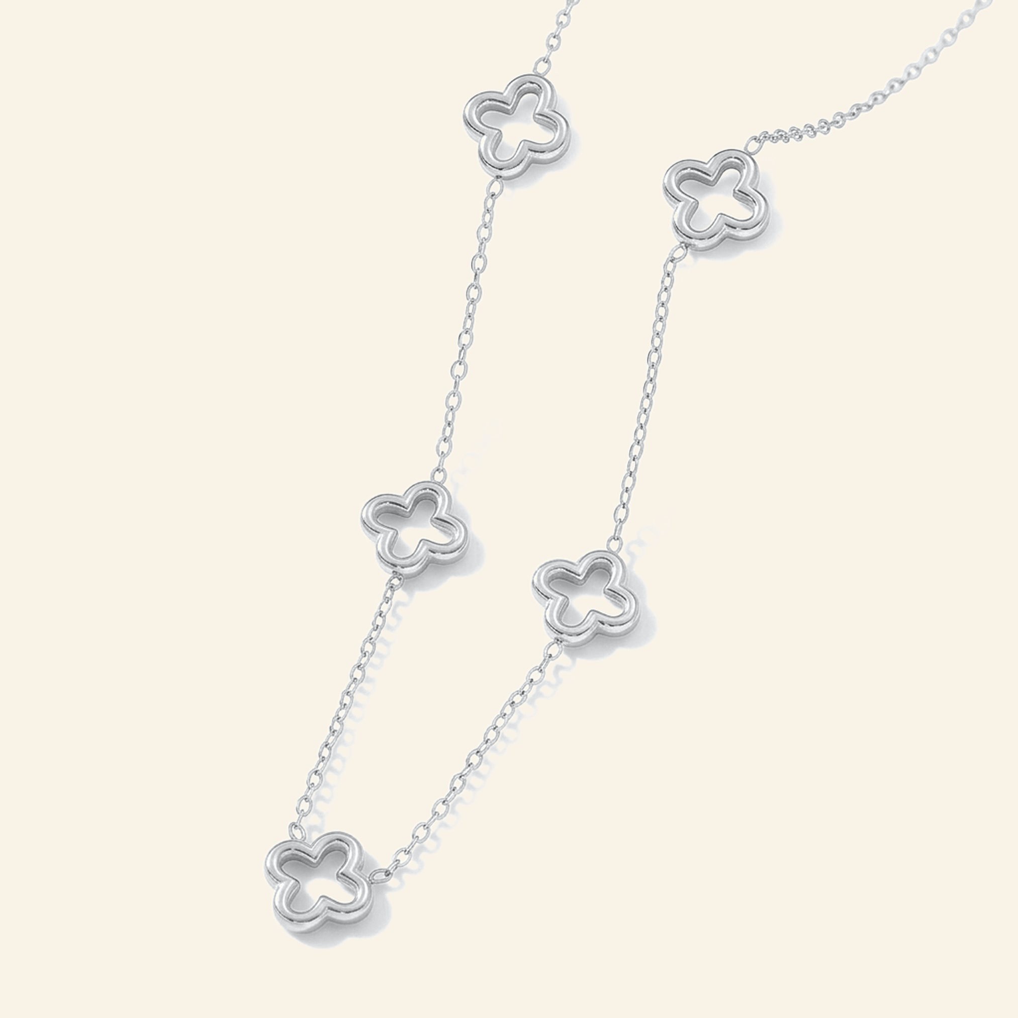 Silver necklace with open hollow four-leaf clover stations